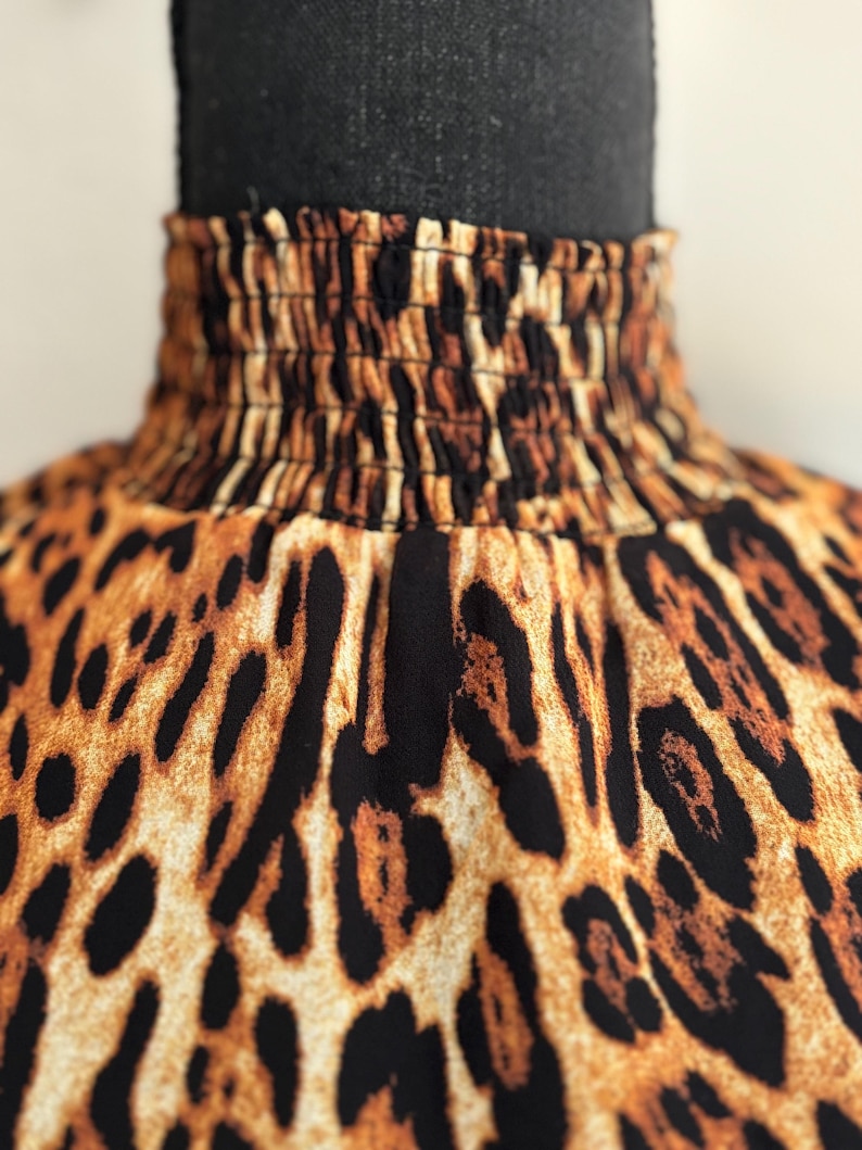 Puede incluir: Primer plano de una tela de estampado de leopardo marr&oacute;n y negro con una banda el&aacute;stica fruncida en la parte superior.