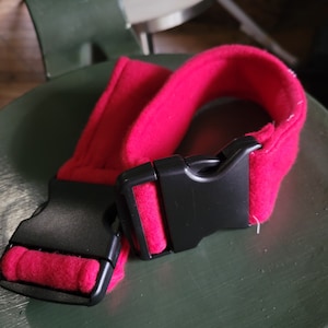 May include: A red fleece dog collar with a black plastic buckle.