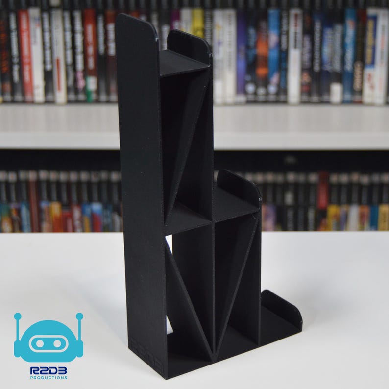 May include: A black, 3D printed, multi-level stand for video game cartridges. The stand has a unique, geometric design with multiple compartments.