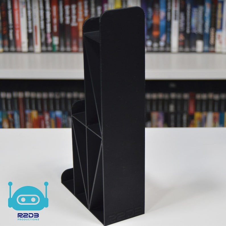May include: Black plastic video game storage stand with multiple compartments. The stand is designed to hold video game cartridges and is labeled "R2D3 Productions".