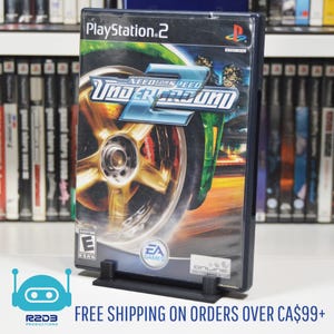 May include: A PlayStation 2 video game case with a black background and a colorful image of a car with the title "Need for Speed Underground 2" printed on the front. The game is rated "E" for Everyone by the ESRB.