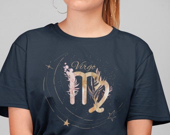 May include: A navy blue t-shirt with a gold Virgo zodiac sign surrounded by a floral design and stars. The text "Virgo" is written in cursive above the sign.