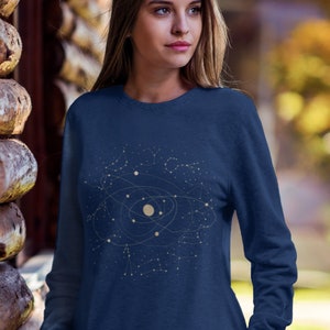 Puede incluir: Una sudadera azul marino con un dise&ntilde;o de constelaci&oacute;n que representa un sistema solar con planetas y estrellas. El dise&ntilde;o es de color dorado claro.
