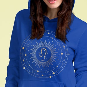 May include: A royal blue hoodie featuring a gold sun and zodiac symbol for Leo. The sun is surrounded by a circle with smaller circles and stars.