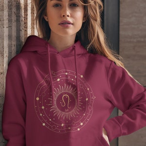 May include: Burgundy hoodie with a gold zodiac design featuring the Leo constellation and the word "Leo" in a circle.