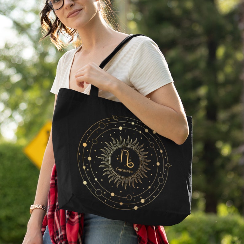 May include: Black tote bag with a gold zodiac symbol and the word "Capricorn" inside a circle of stars and planets.