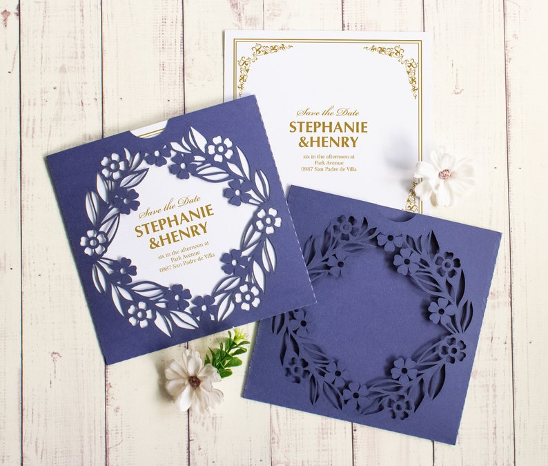 May include: Purple save the date cards with a floral design and the text "Save the Date Stephanie & Henry" in gold lettering.