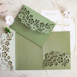 May include: Green laser cut wedding invitation with floral design. The invitation is folded in thirds and has a white inner layer. The text on the invitation reads "The honor of your presence is requested at the marriage ceremony of".