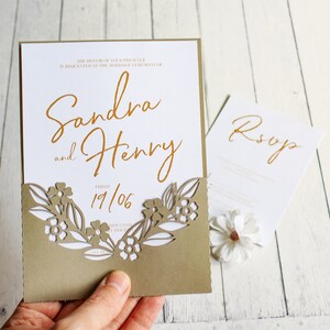May include: A wedding invitation with a laser cut floral design on the front. The invitation is for Sandra and Henry and the date is 19/06. The RSVP card is also visible.