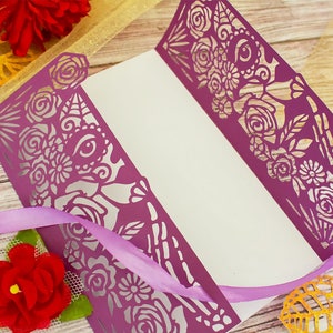 May include: Purple paper card with a cut-out design of flowers and a skull with an eye. The card is folded in half and has a white interior.