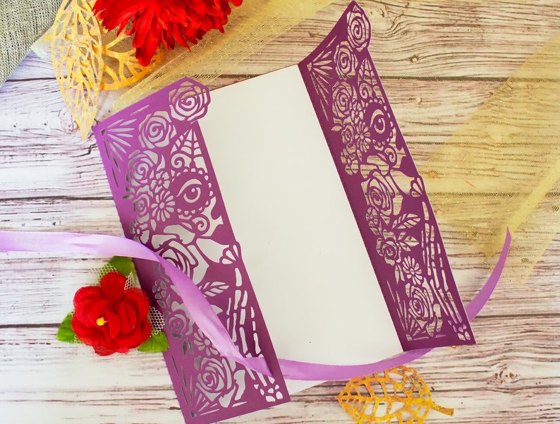 May include: Purple laser cut card with a floral design. The card is folded in half and has a white interior.