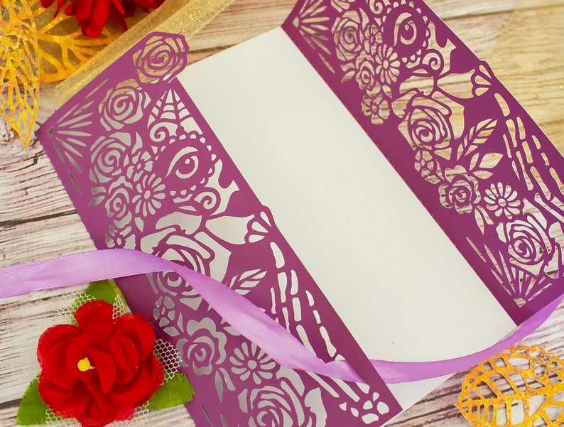 May include: Purple laser cut card with a floral and skull design. The card is folded in half and has a white interior.