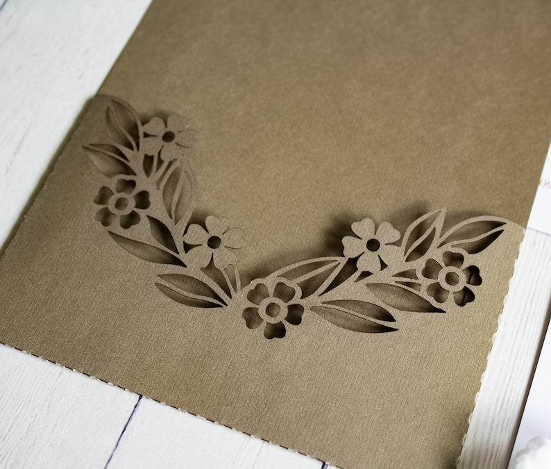 May include: A brown paper envelope with a decorative cut-out design of flowers and leaves around the edge.