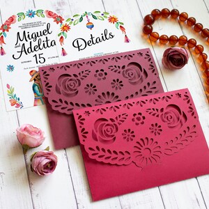 Puede incluir: Dos sobres de papel burdeos con intrincados dise&ntilde;os recortados que representan flores y hojas. Los sobres est&aacute;n sobre una superficie de madera blanca. El texto en el sobre dice "Detalles".