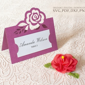 Könnte beinhalten: Lilafarbene Platzkarte mit einem ausgeschnittenen Rosenmuster. Die Karte trägt den Text "Amanda Wilson, Tisch 5".