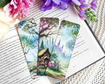 May include: Set of three watercolor bookmarks featuring whimsical scenes. The first bookmark shows a cottage in a forest with a blue sky and white clouds. The second bookmark shows a castle in a forest with a blue sky and white clouds. The third bookmark shows a forest with a blue sky and white clouds.