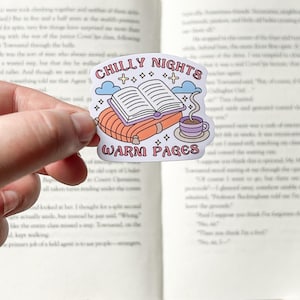 May include: A sticker with a cute illustration of a book, a cup of coffee, and clouds. The text on the sticker reads "Chilly Nights Warm Pages".