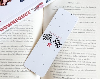 May include: White bookmark with Formula One Girlie text and checkered flag graphics. The bookmark has black polka dots and red ribbon accents. The bookmark is resting on an open book.