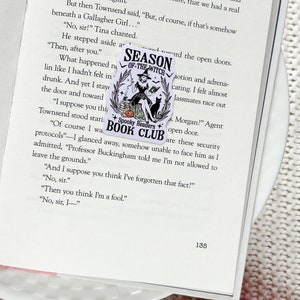 May include: A black and white sticker with a witch holding a black cat. The sticker says "Season of the Witch" and "Spooky Readers Book Club".