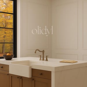 May include: A kitchen island with a white countertop and a farmhouse sink. A bronze faucet is installed. The cabinets are brown with dark knobs. A wooden cutting board rests on the countertop. The word "olidyl" is printed on the wall.