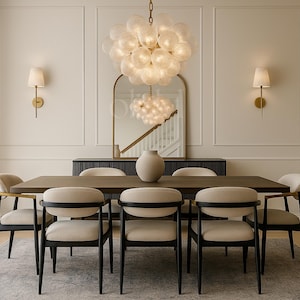 May include: A dining room set featuring a dark wood table, six beige chairs, and a large, round, glass chandelier. A large vase sits on the table. Two wall sconces and a mirror are also visible.