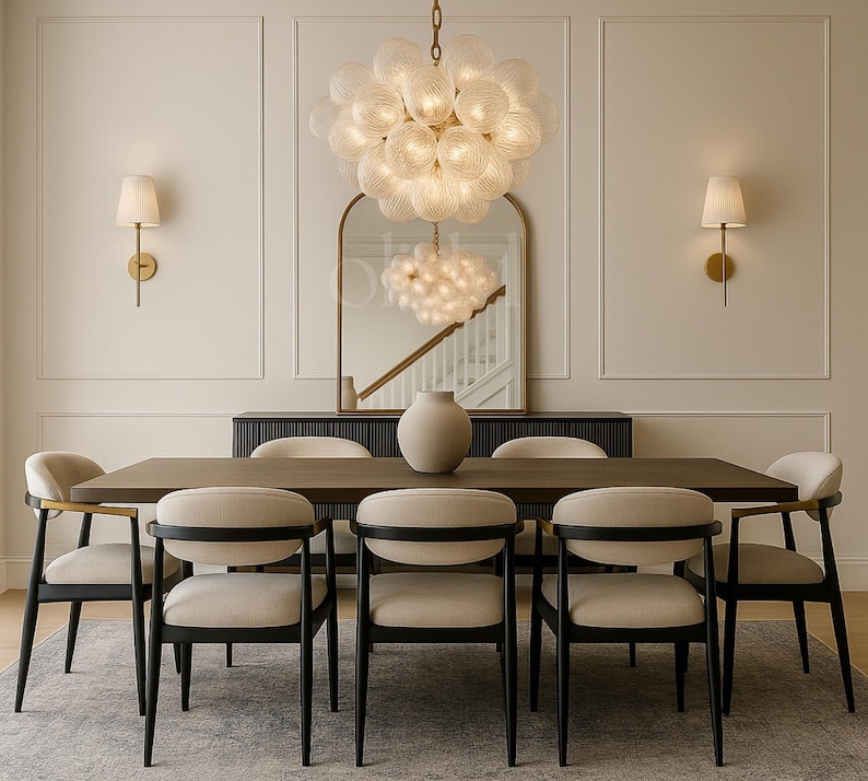 May include: A dining room set featuring a dark wood table, six beige chairs, and a large, round, glass chandelier. A large vase sits on the table. Two wall sconces and a mirror are also visible.