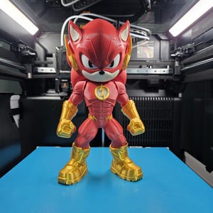 May include: A red and gold action figure of a character that is a hybrid of Sonic the Hedgehog and The Flash. The figure has a red body with gold accents on the boots, gloves, and head. A yellow lightning bolt is on the chest.