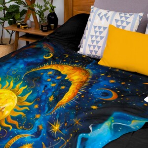Peut inclure: Une couverture en jetée bleue et noire avec un motif céleste représentant un soleil jaune et une lune croissante avec des étoiles.