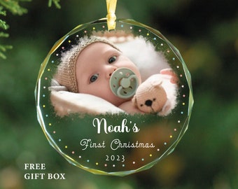 Puede incluir: Un adorno de Navidad de vidrio transparente con una foto de bebé en su interior. El adorno está decorado con estrellas de colores y el texto "Noah's First Christmas 2023".