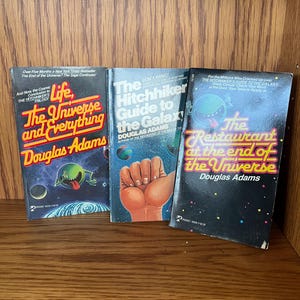St of 4 books by Duaglas Adams So Long, and Thanks for All the Fish, Hitchhiking Gide, Restorans at the end of Universy soft covers