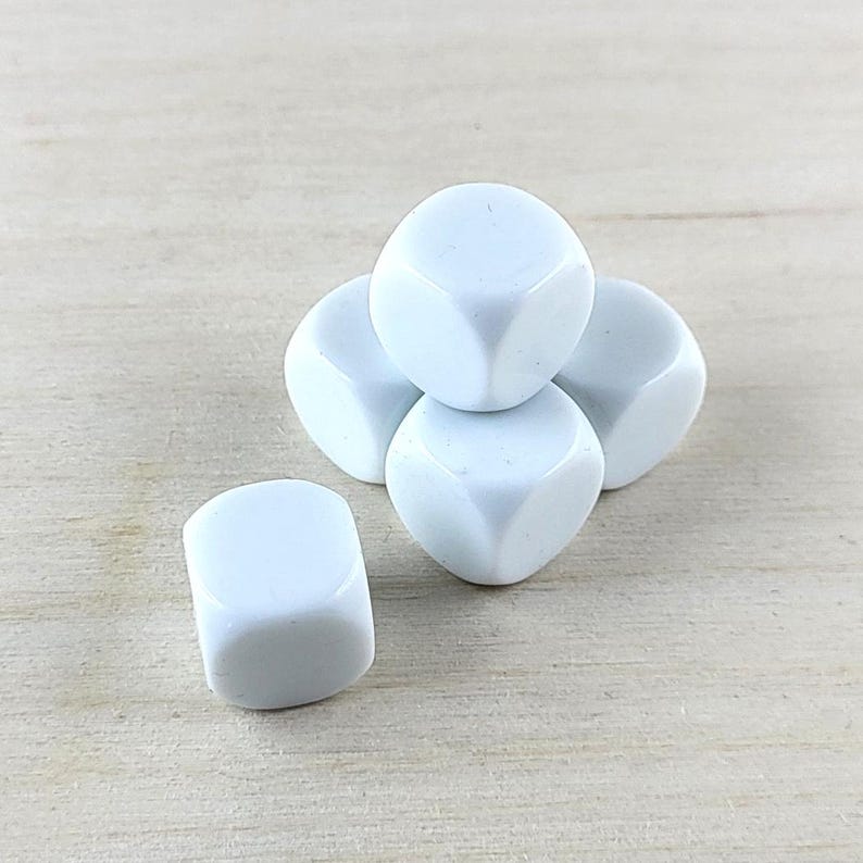 Puede incluir: Cinco dados blancos, apilados en forma de pir&aacute;mide, sobre una superficie de madera clara.