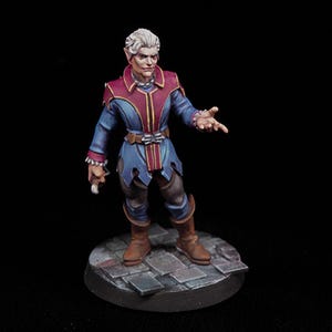 May include: Miniature fantasy figure of an elf-like character. The figure wears a blue tunic with red accents and gold trim, brown boots, and a belt. The figure is holding a small object in one hand and has the other hand outstretched. The figure stands on a stone base.