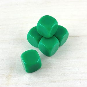 Puede incluir: Cinco dados verdes apilados en forma de pir&aacute;mide sobre una superficie de madera clara.