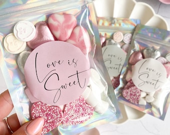 May include: Pink and white heart-shaped candies and marshmallows in a clear plastic bag with a pink and white sticker that says "Love is Sweet".