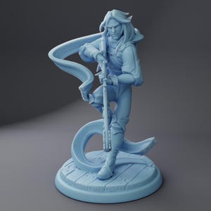 May include: A light blue figurine of a character with long hair, holding a rifle. The figure is posed dynamically, with a flowing scarf-like element. The base is a light blue wooden platform.