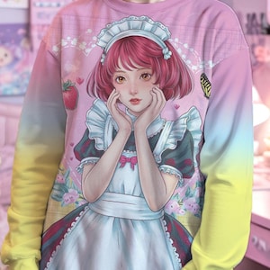 May include: A pink and yellow ombre sweatshirt with a graphic print of a cartoon maid with pink hair and a white apron. The maid is holding her hands to her face and looking at the viewer. The sweatshirt has a crew neck and long sleeves.