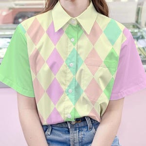 May include: A pastel green, yellow, and pink short-sleeved button-up shirt with a diamond pattern. The shirt has a pocket on the left side.