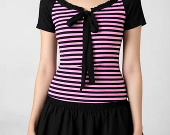 Puede incluir: Top a rayas negras y rosas con lazo negro y falda negra. El top tiene mangas cortas y cuello redondo. La falda es corta y acampanada. El conjunto combina elementos casuales y femeninos.