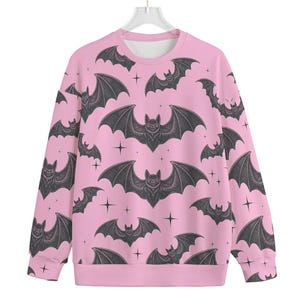 May include: Pink sweatshirt with a black bat pattern. The bats are repeated throughout the sweatshirt.
