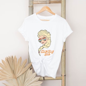 Puede incluir: Camiseta blanca con una imagen de dibujos animados de Elsa de Frozen con gafas de sol y el texto "Best Day Ever".