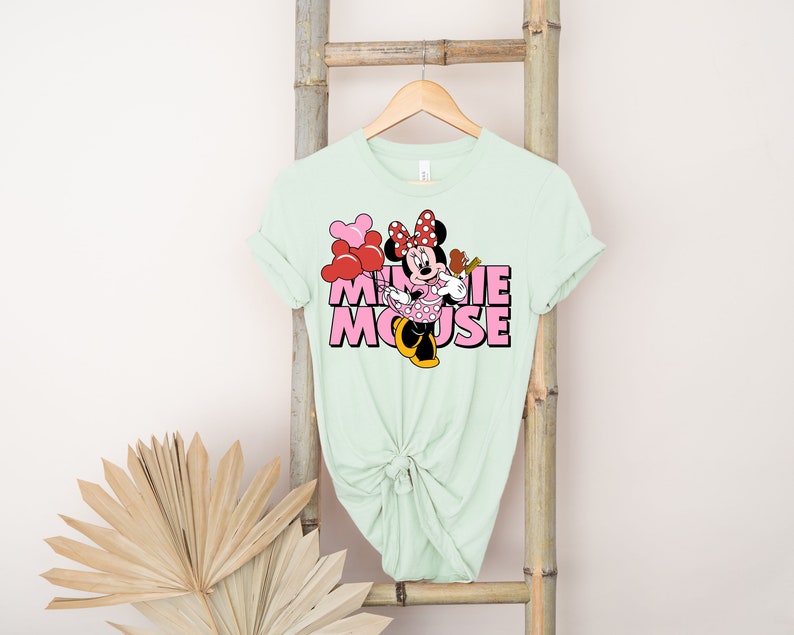 May include: A light green t-shirt with a pink and red graphic of Minnie Mouse with the text "Minnie Mouse" in pink letters.
