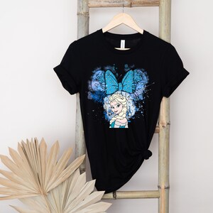 May include: Black t-shirt with a blue and white graphic of Elsa from Frozen wearing a blue bow. The graphic has a watercolor effect.