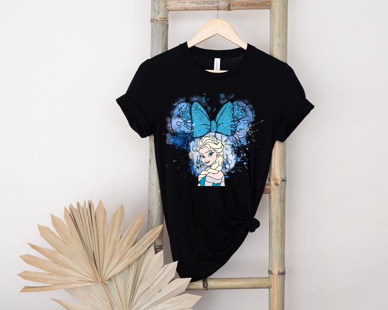 May include: Black t-shirt with a blue and white graphic of Elsa from Frozen wearing a blue bow. The graphic has a watercolor effect.