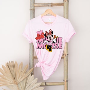 May include: Pink t-shirt with a graphic of Minnie Mouse holding balloons and the text "Minnie Mouse" in pink letters.