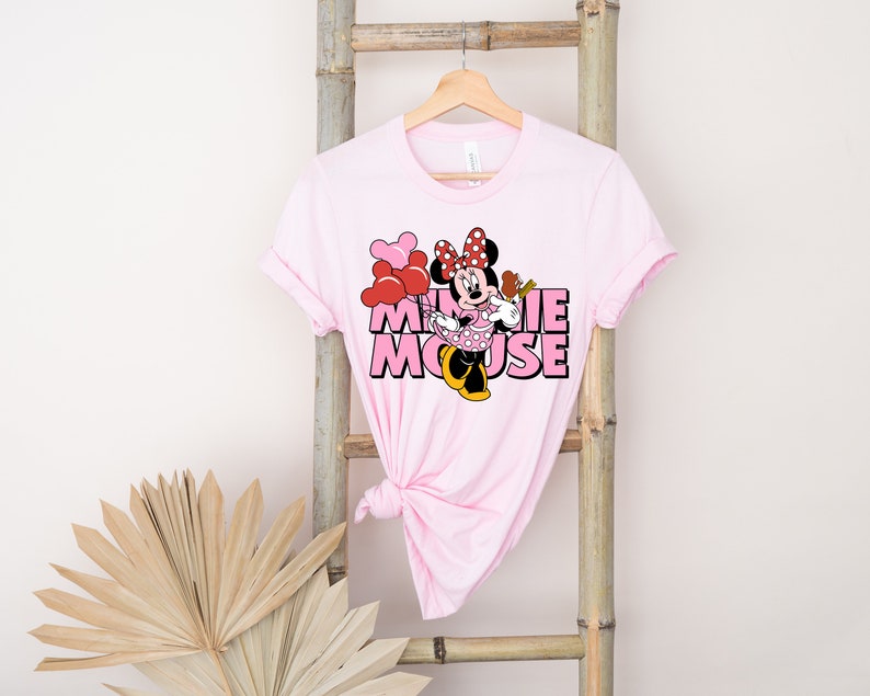 May include: Pink t-shirt with a graphic of Minnie Mouse holding balloons and the text "Minnie Mouse" in pink letters.