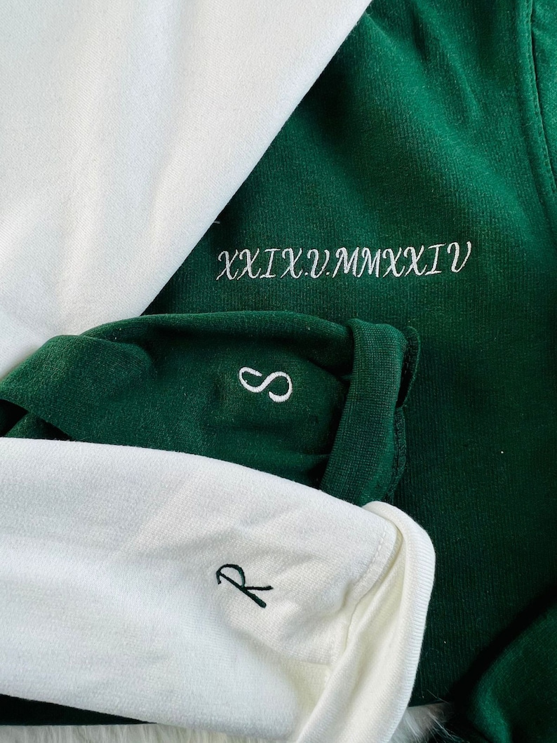 Peut inclure: Deux chemises &agrave; manches longues, une blanche et une verte. La chemise verte a le texte "XXIX.V.MMXXVI" brod&eacute; sur le devant. La chemise blanche a un petit "R" brod&eacute; sur le devant.