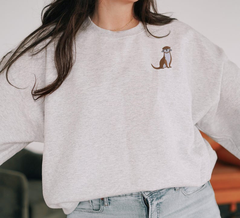 Peut inclure: Un sweat-shirt gris avec une petite loutre brod&eacute;e sur la poitrine gauche.