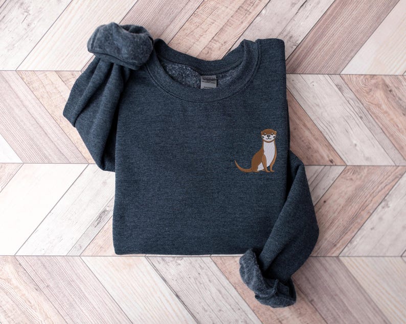Peut inclure: Un sweat-shirt gris fonc&eacute; avec un graphique d'une loutre brune et blanche sur la poitrine gauche.