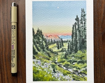 Könnte beinhalten: Aquarellmalerei einer Berglandschaft mit Bach, Bäumen und Sonnenuntergang. Das Gemälde befindet sich auf weißem Papier, mit einem schwarzen Micron 005 Archivtintenstift links. Der Himmel ist hellblau mit einem weißen Mond.