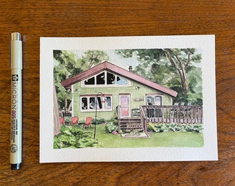 Könnte beinhalten: Aquarellmalerei eines grünen Hauses mit braunem Dach, umgeben von Bäumen und Grün. Das Haus hat eine Terrasse und ein paar rote Stühle im Garten. Ein schwarzer Stift befindet sich auf der linken Seite des Bildes.